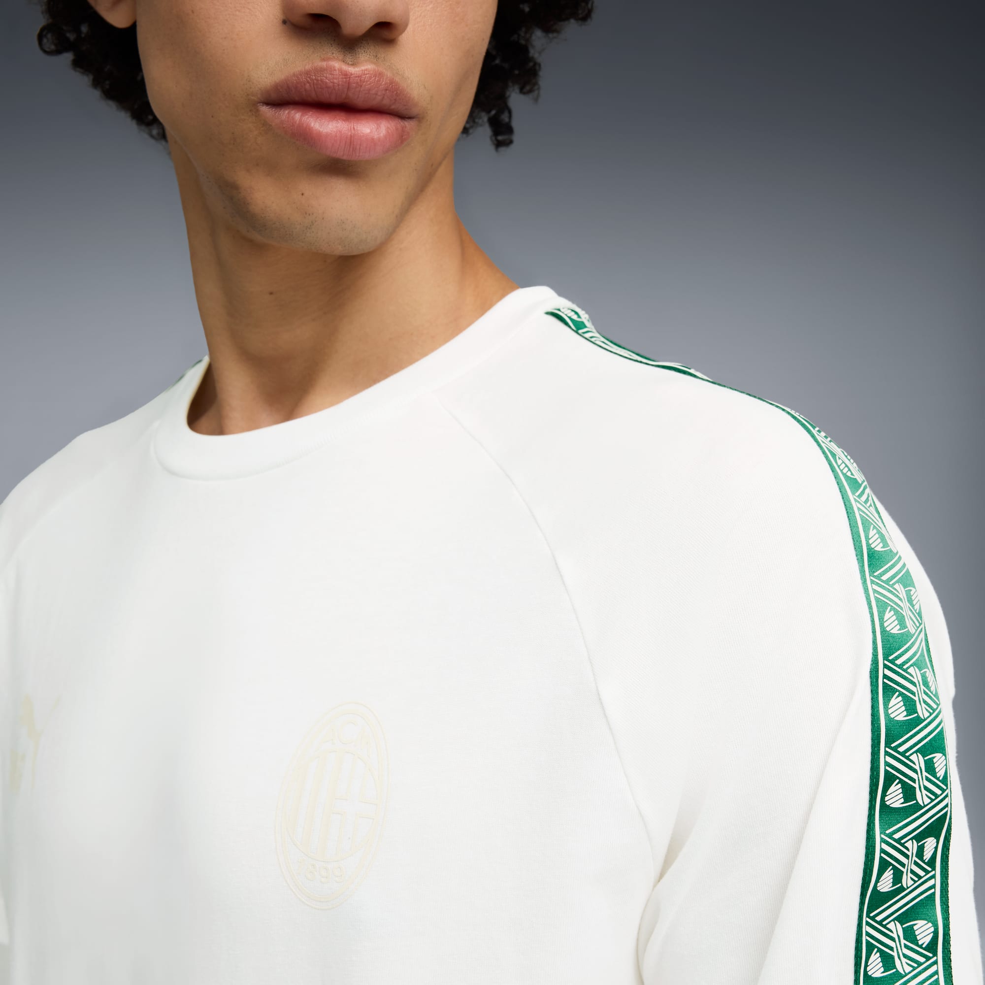 A model wears a white sweatshirt with green stripe detail against a grey backdrop.