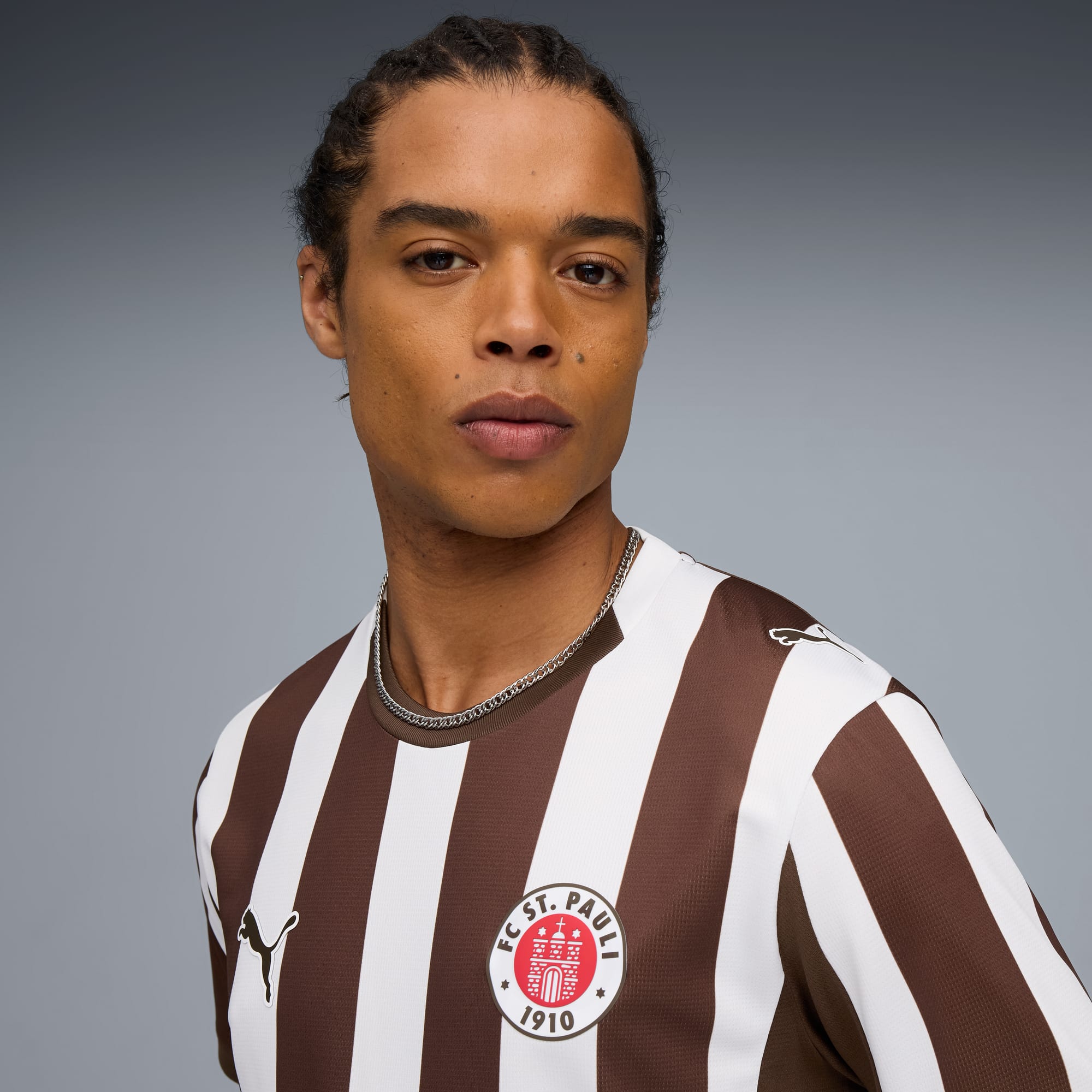 Een model draagt een bruin-wit gestreept shirt met een voetbalclublogo.