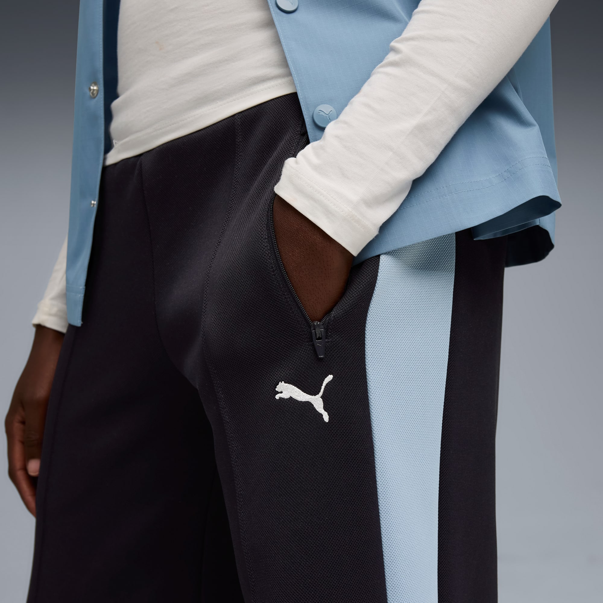 Vor grauem Hintergrund posiert ein Model mit einer Hand in der Hosentasche.