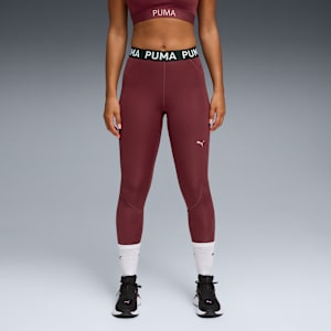 A model stands against grey wearing a maroon sports bra, leggings, socks and trainers.