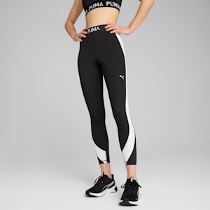 A model poses against a grey backdrop, showcasing black leggings with a white stripe and black trainers.