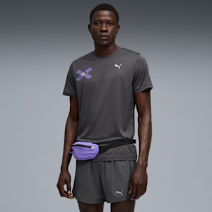 A model stands against a grey backdrop, wearing a grey t-shirt, shorts and a purple waist bag.