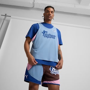 A model poses in front of a white background wearing a blue t-shirt, vest and patterned shorts.