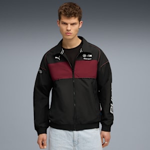 A model poses against a grey backdrop, wearing a black and red Motorsport jacket.