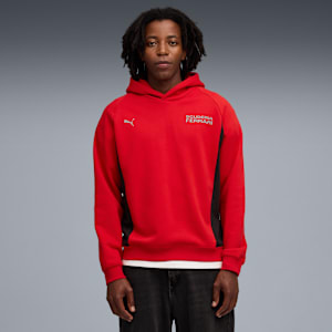 Against grey, a model wears a red Scuderia Ferrari hoodie and dark jeans, facing forward.