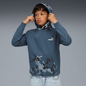 Against grey, a model adjusts a blue Puma hooded top with camo accents.