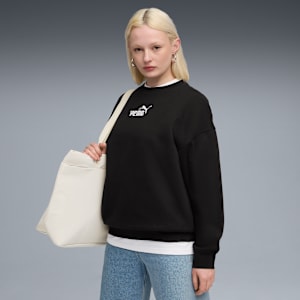 A model poses against grey, wearing a black Puma sweatshirt and carrying a cream tote bag.