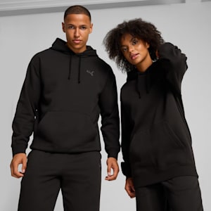 Two models pose in front of a grey background, wearing black hoodies and trousers.