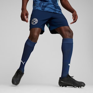 A model in a running pose on a grey background, wearing a blue kit and black football boots.