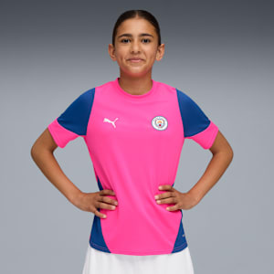 A model poses against a grey backdrop, wearing a pink and blue sports shirt.