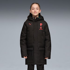 A model poses against a grey backdrop, wearing a black padded coat with red logo details.