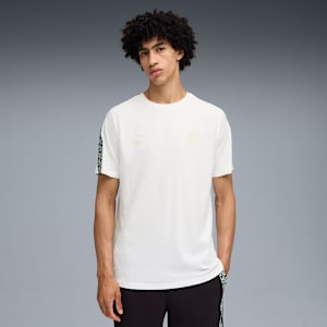 A model stands against grey wearing a white t-shirt and black bottoms with patterned trim.