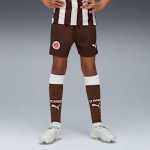 On grey, a model wears a St. Pauli kit: brown shorts, socks and white running shoes.
