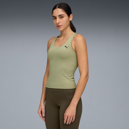 Sur fond gris, un mannequin pose en haut vert clair et legging vert foncé.