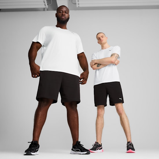 Two models stand in front of a grey backdrop wearing t-shirts, shorts and trainers.