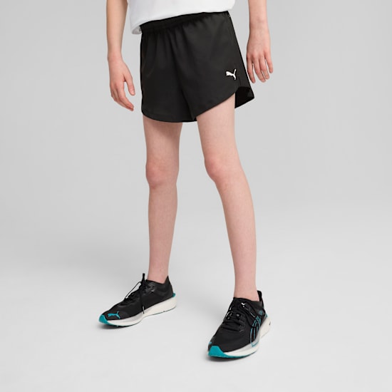 Op grijs draagt een model een witte top, zwarte shorts en hardloopschoenen, klaar om te rennen.