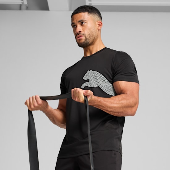 A model against a grey backdrop pulls on a black resistance band wearing a black tee.