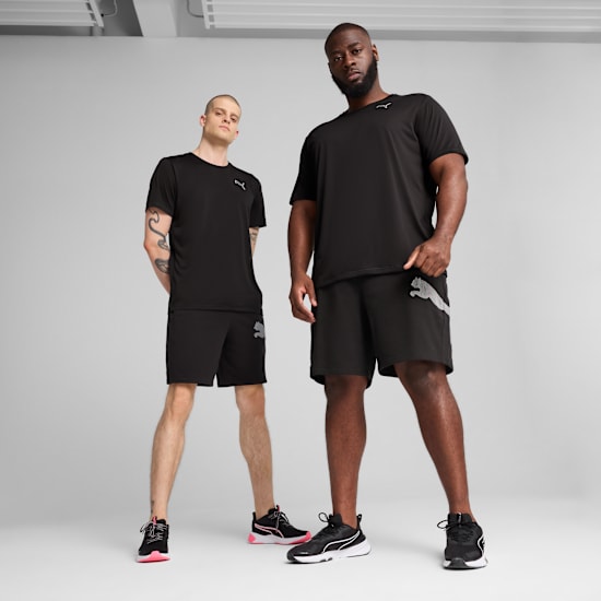 Two models pose against grey backdrop, wearing black activewear with matching trainers.