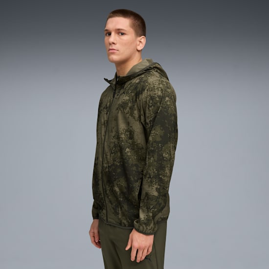 Against grey, a model poses in camo jacket and trousers, looking at the camera.