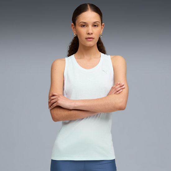 A model with crossed arms wears a light top against a grey backdrop.