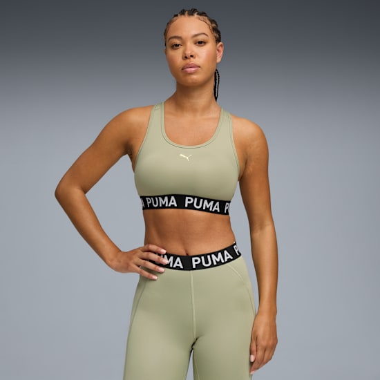 A model poses against grey, wearing a sage sports bra and leggings with a 'PUMA' band.