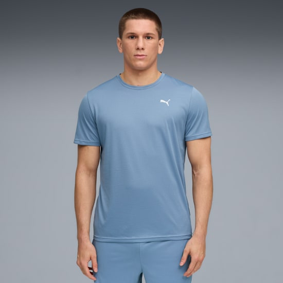 Against grey, a model stands wearing a blue t-shirt and matching shorts.