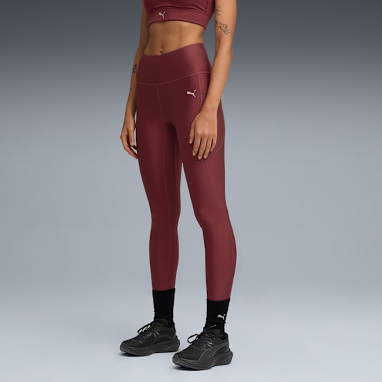Against grey, a model wears burgundy leggings and black trainers in a standing pose.
