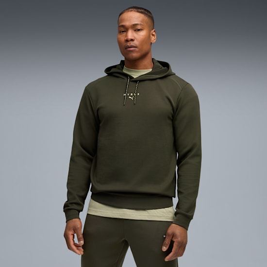 A model stands against grey backdrop wearing a green hoodie and matching sweatpants.