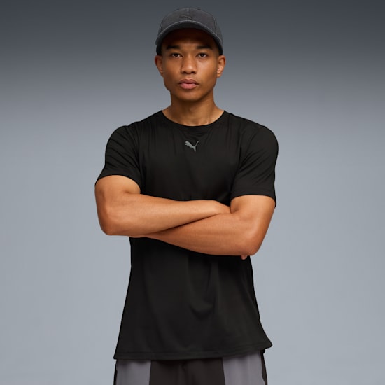 Un mannequin, bras croisés, porte un t-shirt noir et une casquette sur fond gris.