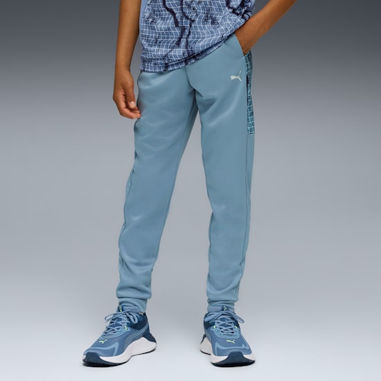 Un modèle pose sur fond gris, portant un pantalon bleu et des baskets assorties.