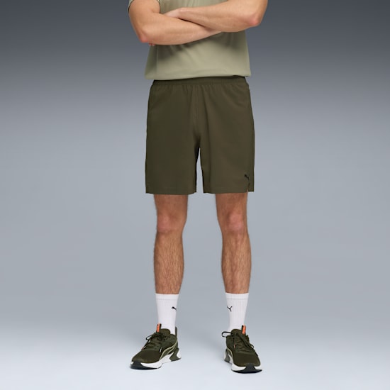 Vor grauem Hintergrund steht ein Model mit T-Shirt, Khaki-Shorts, Socken und Laufschuhen.