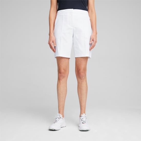 Un modèle sur fond gris porte un short blanc et des baskets blanches.