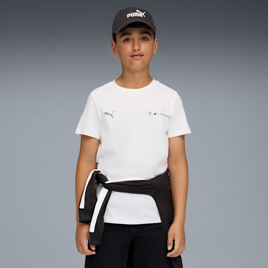 Ein Model steht vor grauem Hintergrund, mit Grafik-T-Shirt und Puma-Kappe.