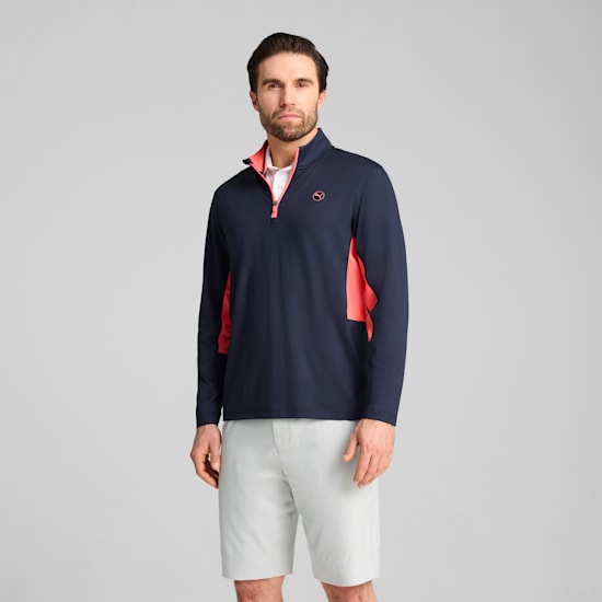 A model stands against a grey background, wearing a navy top and light shorts.