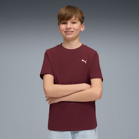 Un modello a braccia conserte indossa una t-shirt bordeaux su sfondo grigio.