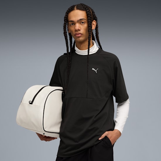 Un mannequin sur fond gris tient un sac blanc, portant un haut noir avec un sous-pull blanc.
