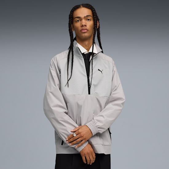 Against grey, a model poses wearing a grey jacket over shirt and tie.