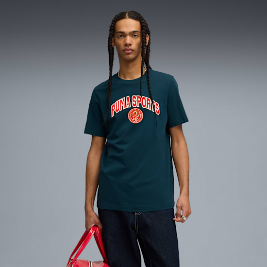 Un modello posa su sfondo grigio, indossa una t-shirt verde acqua, jeans e tiene una borsa rossa.