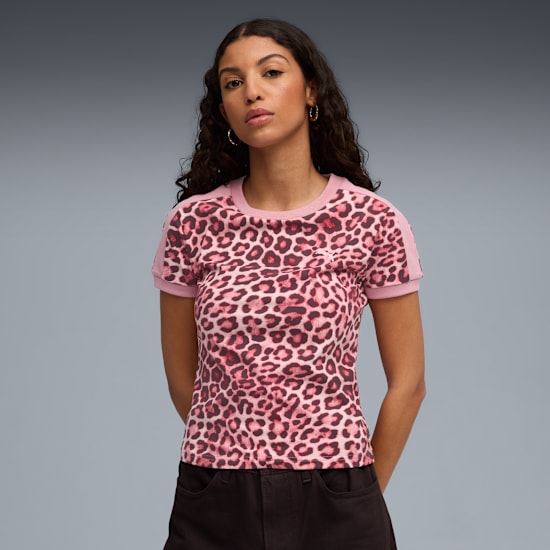 Model poses against grey; wearing a pink, leopard-print tee and dark trousers.