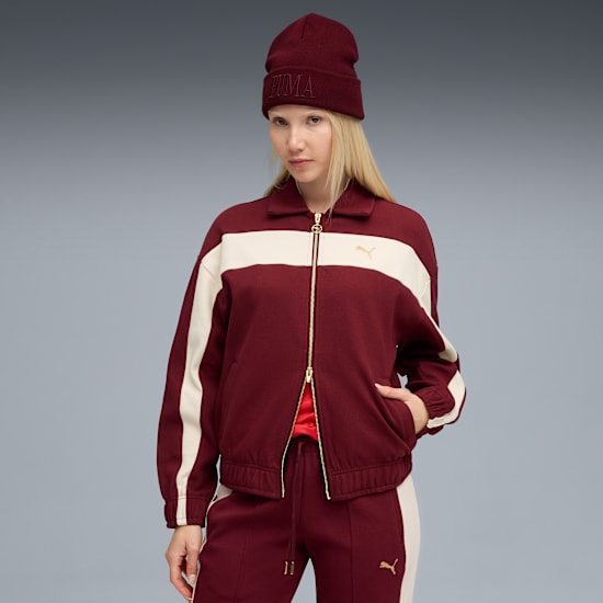 A model poses against grey wearing a burgundy hat, jacket and trousers with cream stripes.