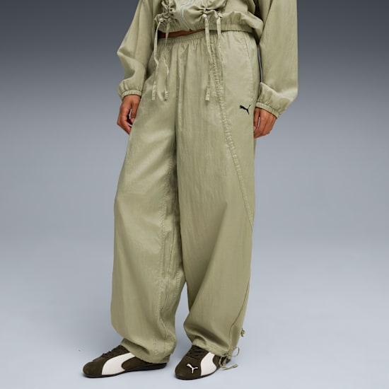 Vor grauem Hintergrund trägt ein Model eine lockere, hellgrüne Hose und dunkelgrüne Turnschuhe.