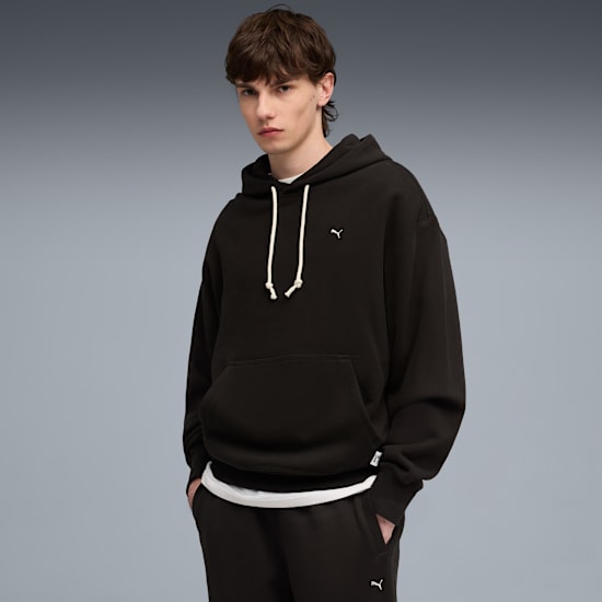 A model poses against grey, wearing a dark hoodie and matching sweatpants.