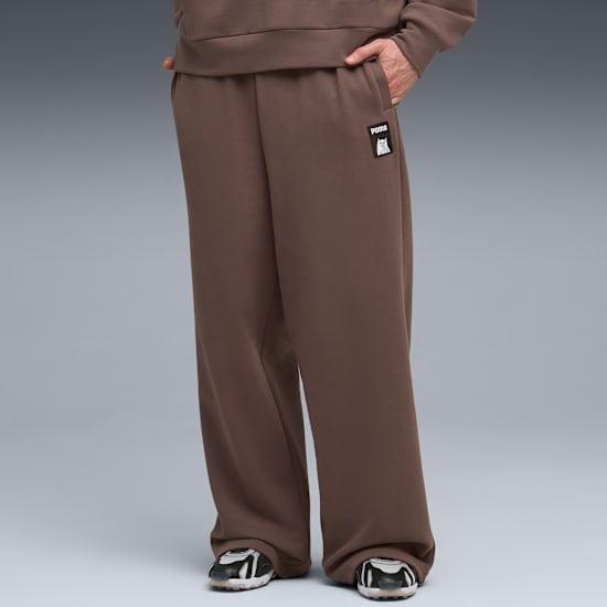 A model on grey shows brown sweatpants with a logo and trainers.