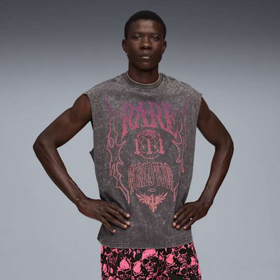 A model poses against a grey backdrop, wearing a graphic grey top and skull-print shorts.
