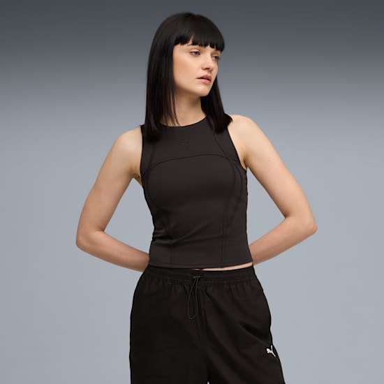 Ein Model posiert vor grau in schwarzem Top und Shorts, Hände an den Hüften.