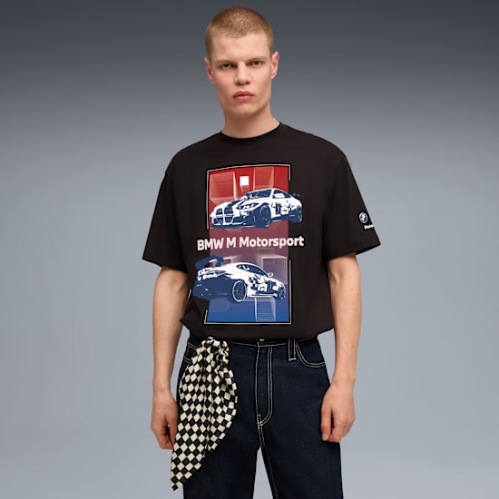 Ein Model vor grauem Hintergrund mit BMW Motorsport T-Shirt und Schachbrettmuster-Tuch.