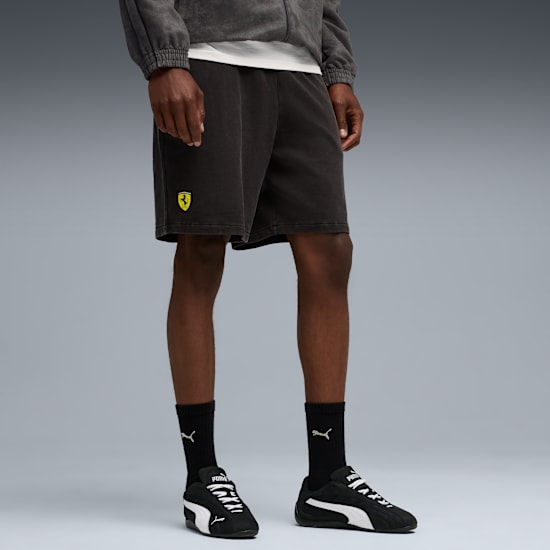 Against grey, a model wears a jacket, shorts with logo, Puma socks and trainers.