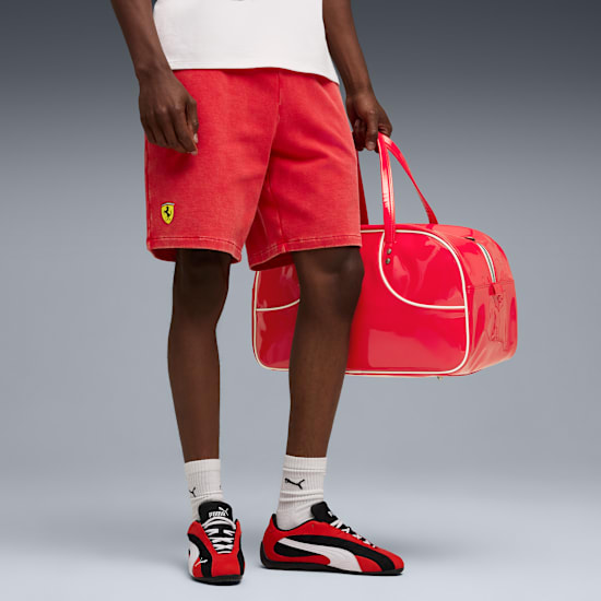 Op grijs houdt een model een rode tas vast, draagt een rode korte broek en zwart-rood-witte sneakers.