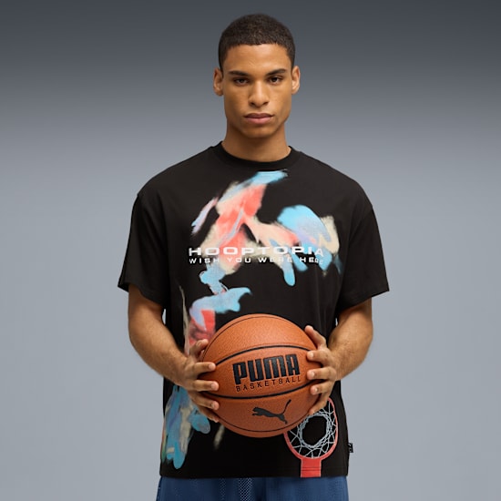 Model holds a basketball wearing a graphic black t-shirt against a grey backdrop.