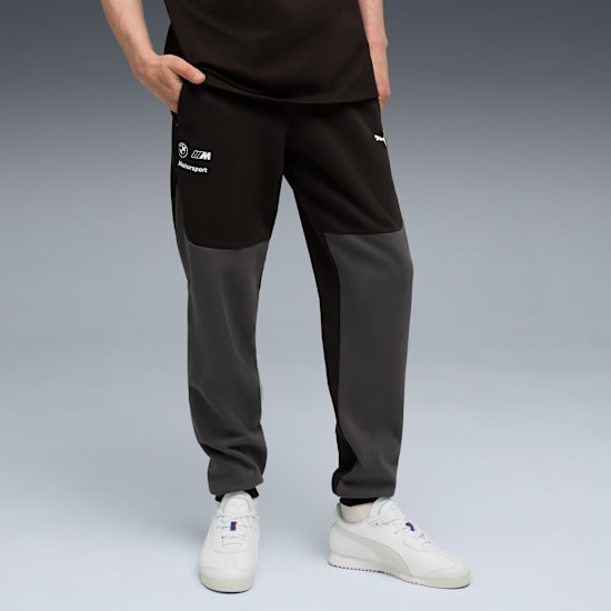 Against grey, a person models two-tone jogging bottoms and white trainers.